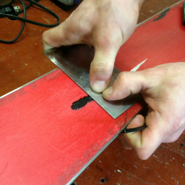 Pressing down on ski base weld material.